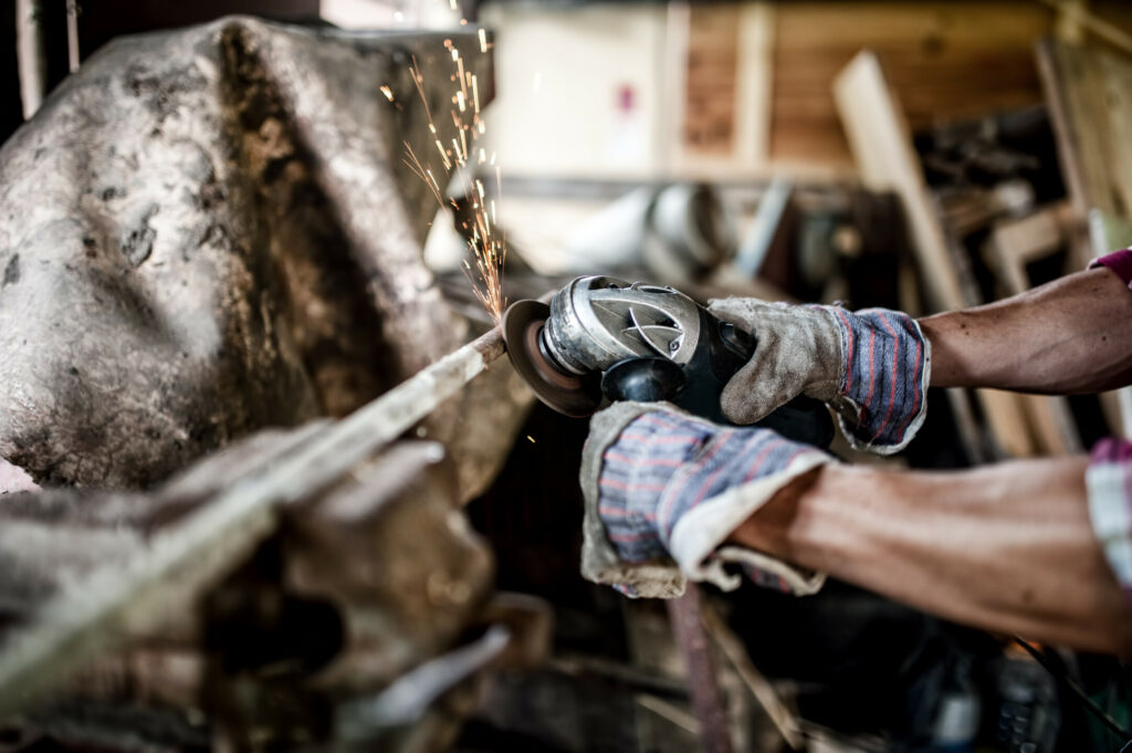 worker polishing and cutting metal with angle grinder, power too